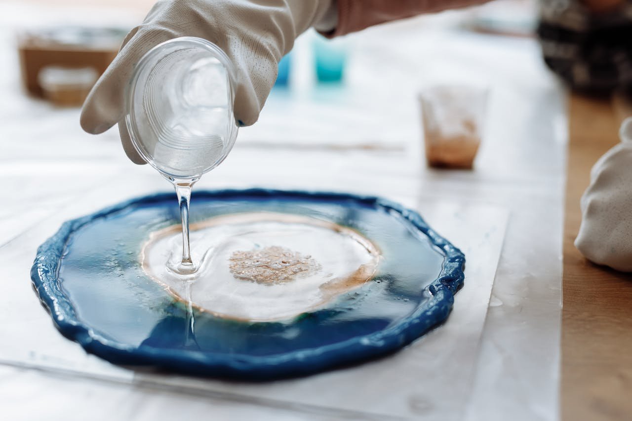 Detailed image of resin art being created with gloves and a plastic cup.